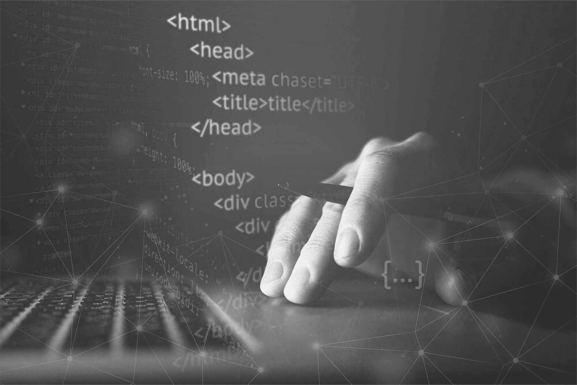 Main sur un clavier qui tient un stylo, des ecritures de code en premier plan.